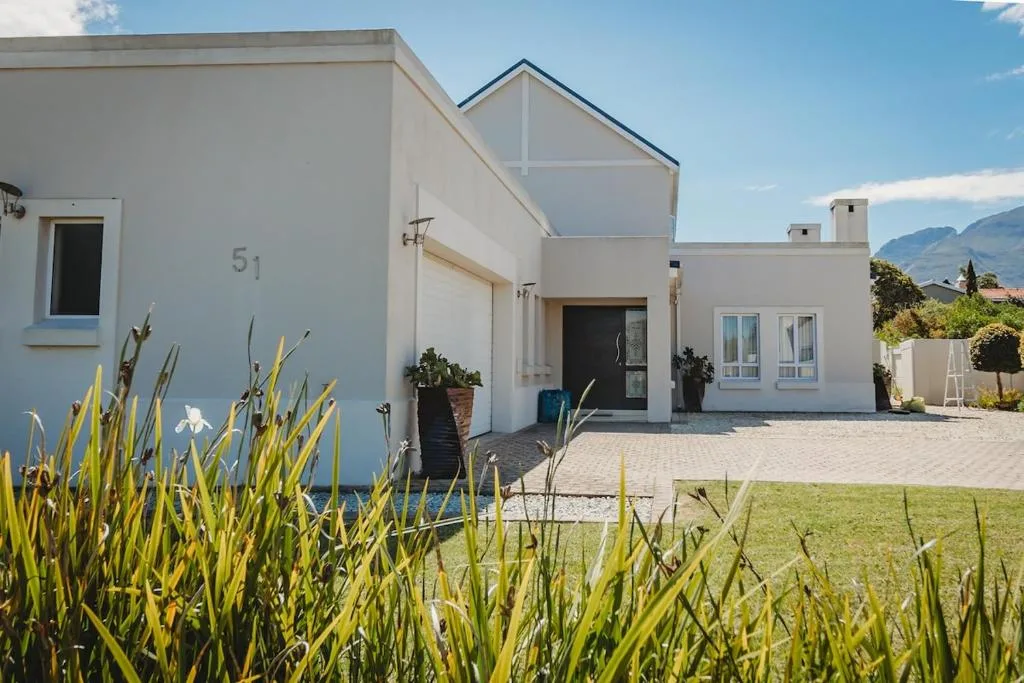 Modern white house with pitched roof and manicured garden entrance