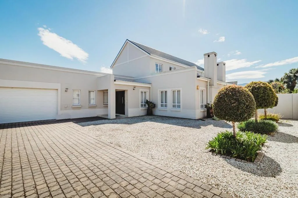 Modern white house with garage, landscaped driveway, and topiary shrubs