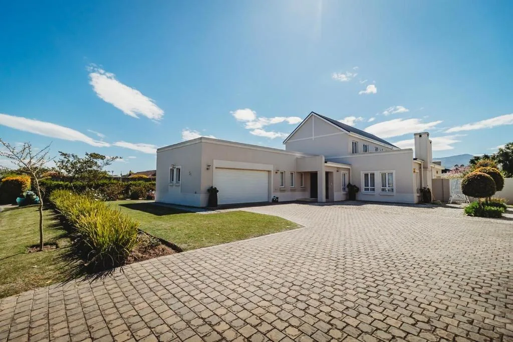 Modern white home with garage and manicured gardens under clear sky