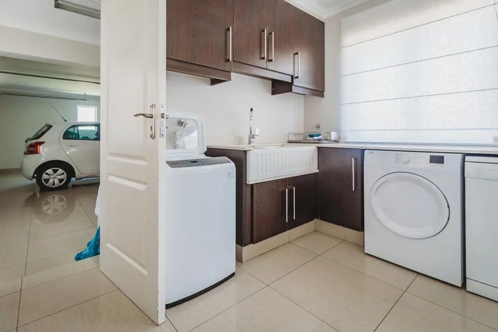 Modern kitchen with washing machine, dryer, sink and dark cabinetry
