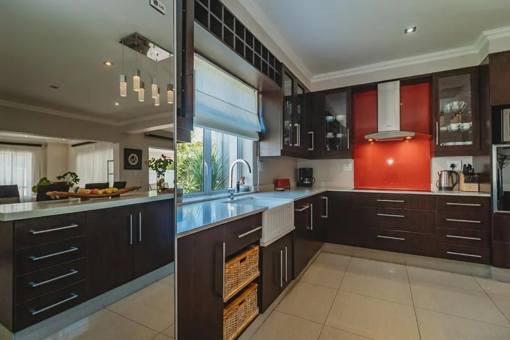 Modern kitchen with dark cabinetry, red backsplash, and blue countertops