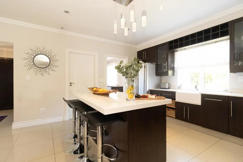 Modern kitchen with black cabinetry, white countertop island, and pendant lighting
