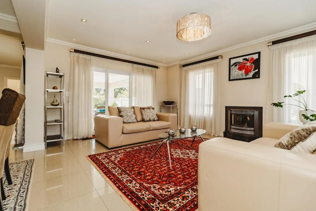 Spacious lounge with cream sofa, fireplace, and water views through glass doors