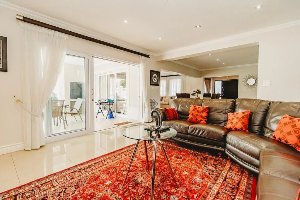 Spacious living room with leather sofa, orange cushions, and glass doors to deck