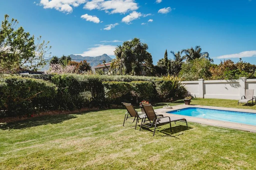 Swimming pool with lounge chairs, manicured lawn, and mountain views beyond