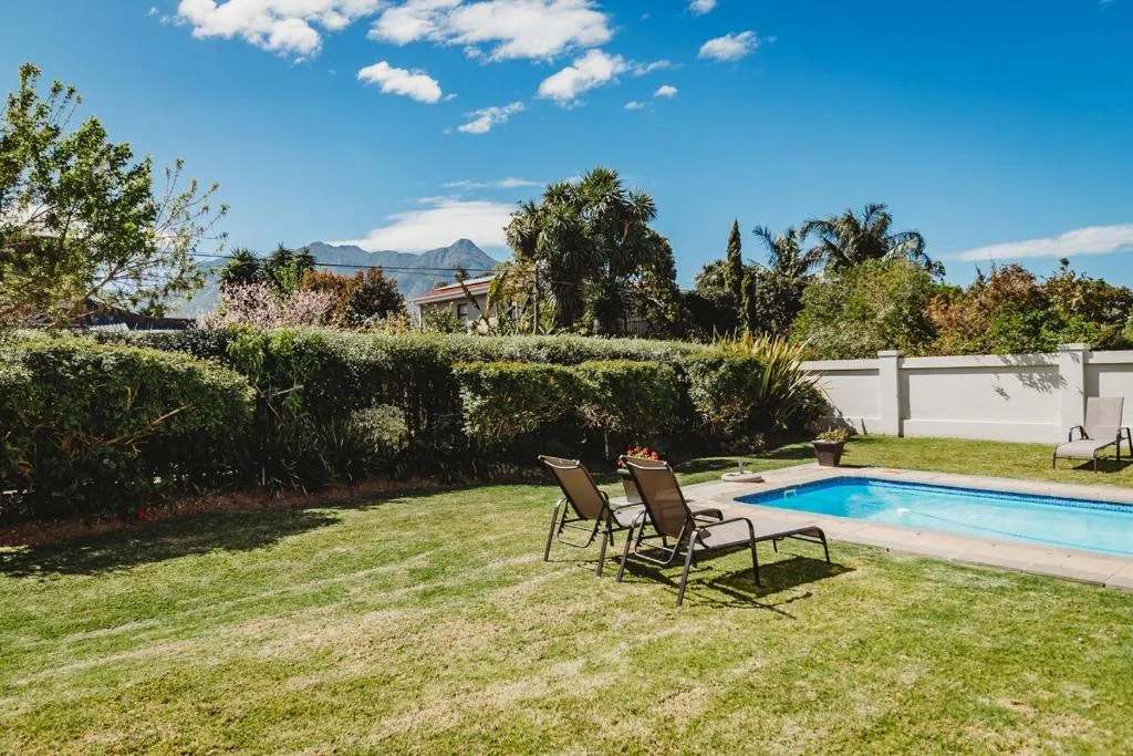 Sparkling swimming pool with loungers on manicured lawn and mountain views