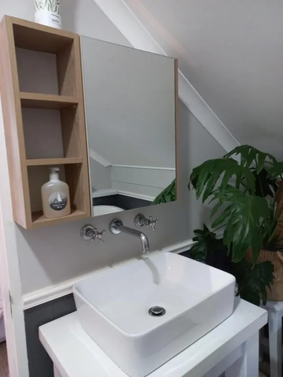 Modern bathroom vanity with white vessel sink and wooden shelving unit