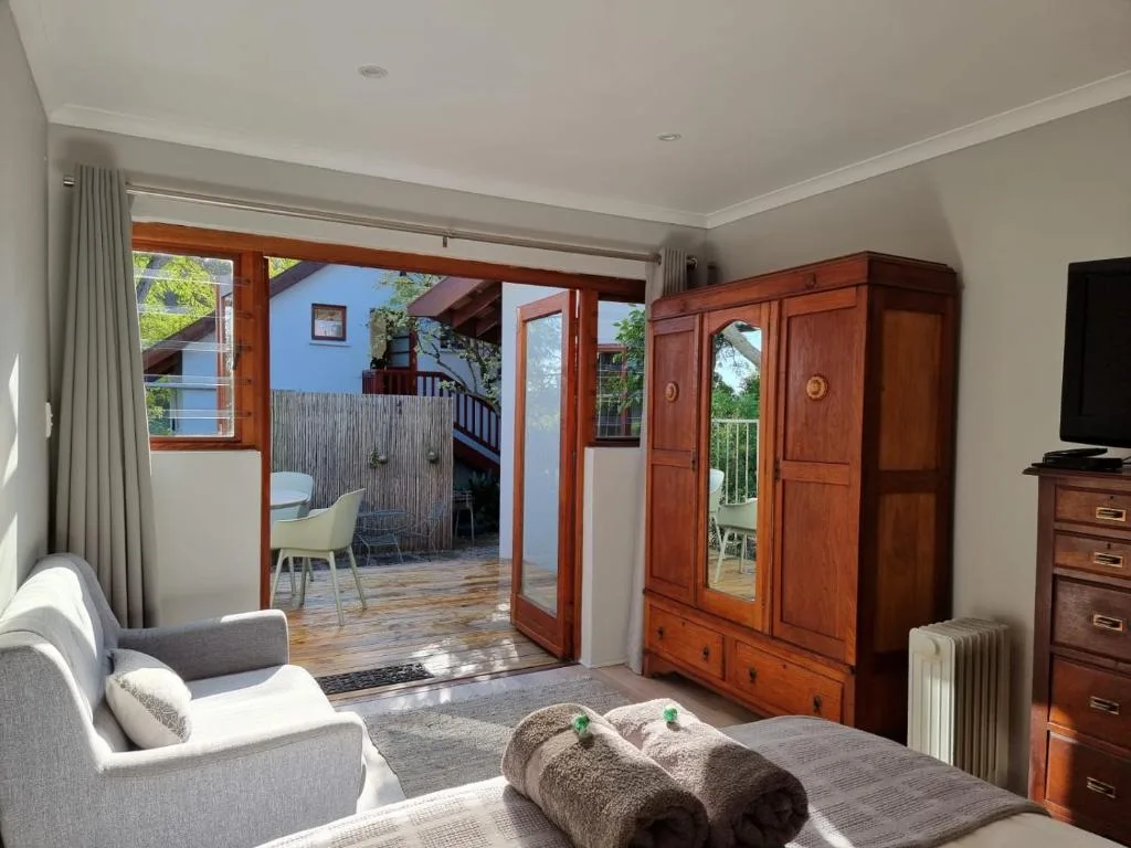 Spacious bedroom with bed, armchair, wooden wardrobe, and deck access