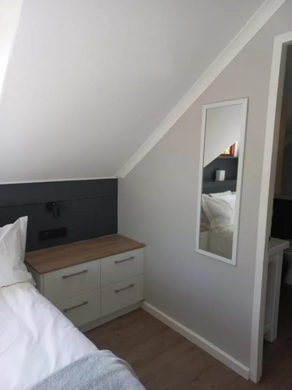 Cozy bedroom with sloped ceiling, bed, dresser, and mirror