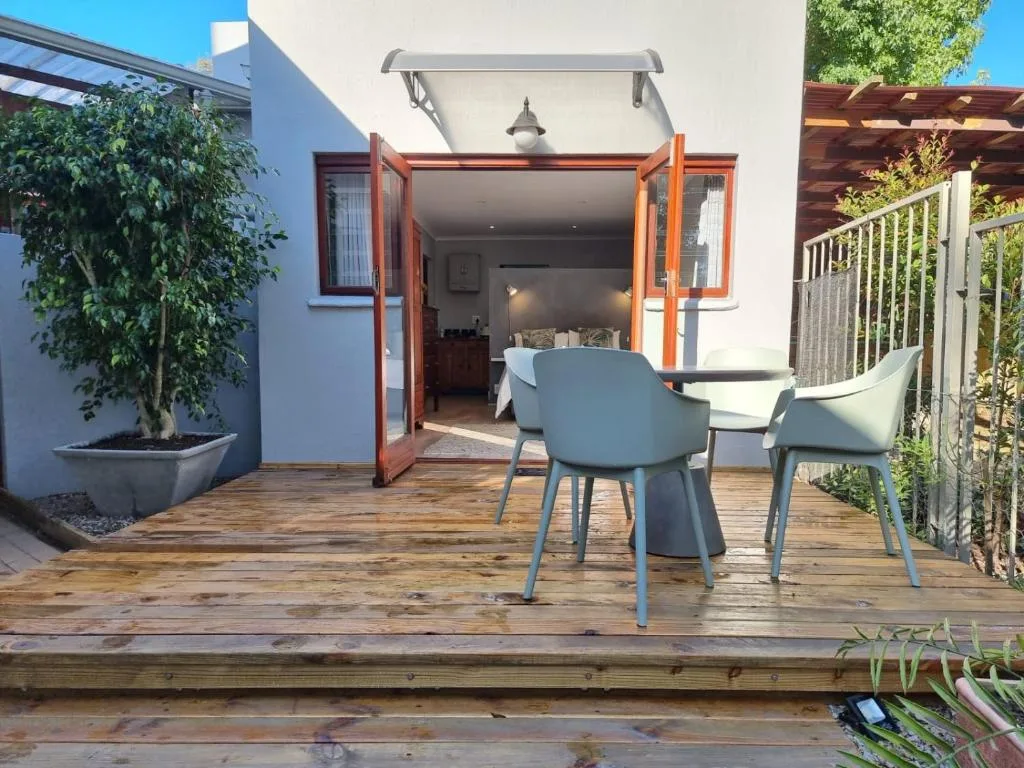 Wooden deck with dining chairs and table, white walls, open glass doors