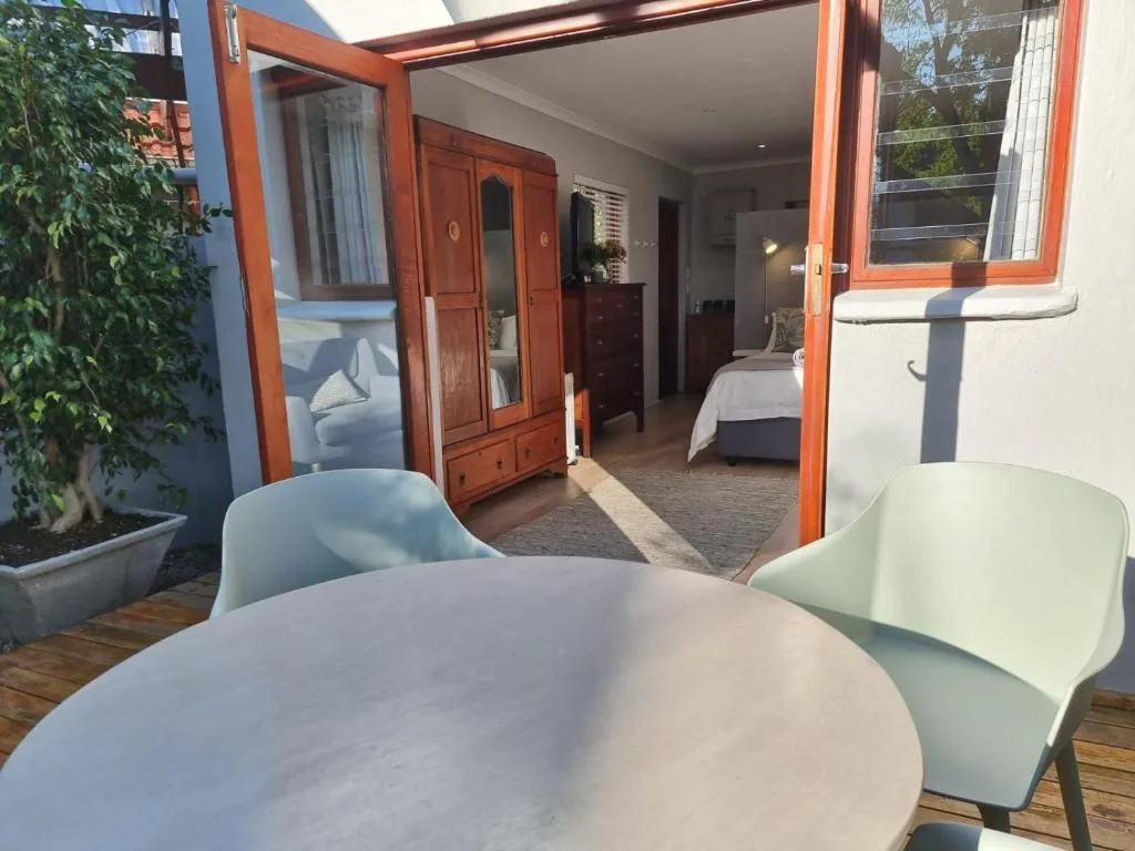 Outdoor patio with round table, chairs, and open doors to bedroom