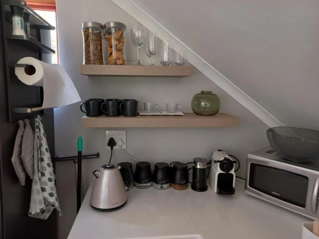 Kitchen shelving with mugs, glasses, cereals, and coffee appliances