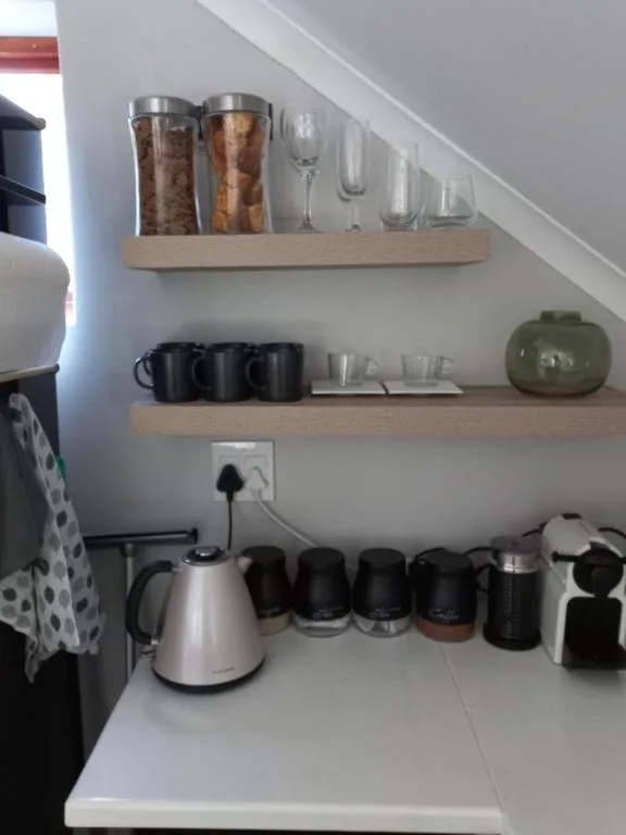 Kitchen shelf with coffee mugs, glasses, kettle, and storage containers