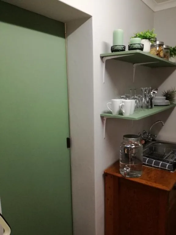 Green painted door with wall-mounted shelves displaying kitchenware and decor