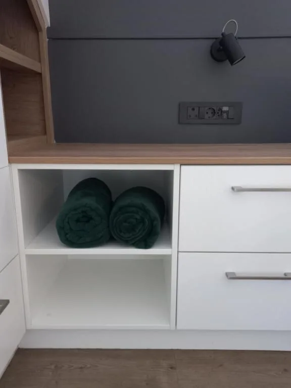 Modern built-in storage shelving with rolled towels and electrical outlets