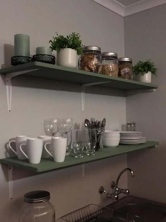 Open shelving with dishware, glassware, candles, and decorative plants