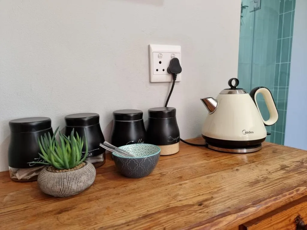 Kitchen counter with electric kettle, storage containers, succulent plant, and power outlet