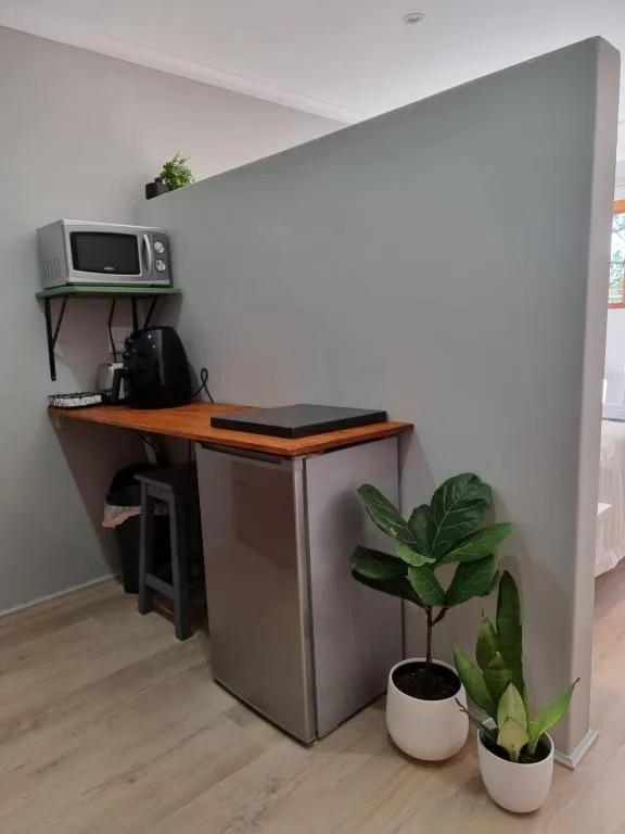Compact kitchenette with microwave, mini fridge, and wooden countertop workspace