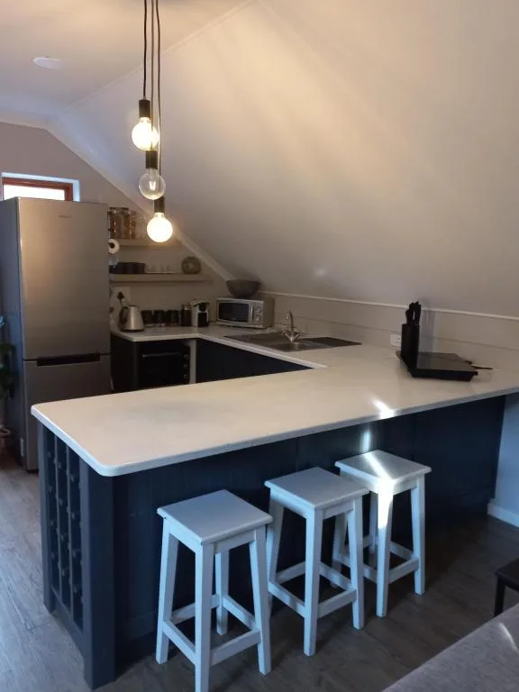 Modern kitchen with dark island, white countertop, and pendant lighting fixtures