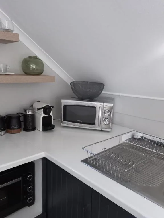 Modern kitchen corner with microwave, coffee maker, and dish rack