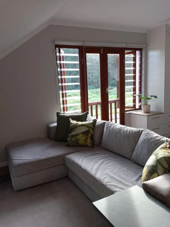 Bright lounge with gray sectional sofa facing glass doors overlooking garden