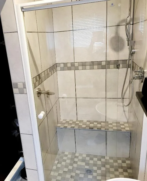 Clean shower enclosure with cream tiles and checkered border trim