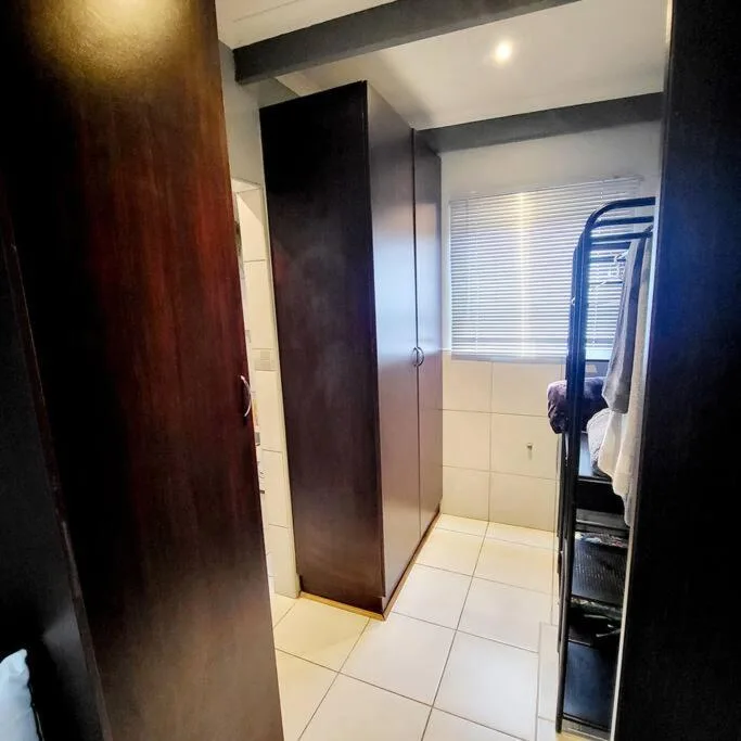 Modern bathroom with shower enclosure, towel rack, and cream tile flooring
