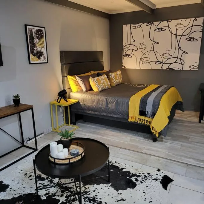 Modern bedroom with queen bed, yellow accents, and abstract wall art