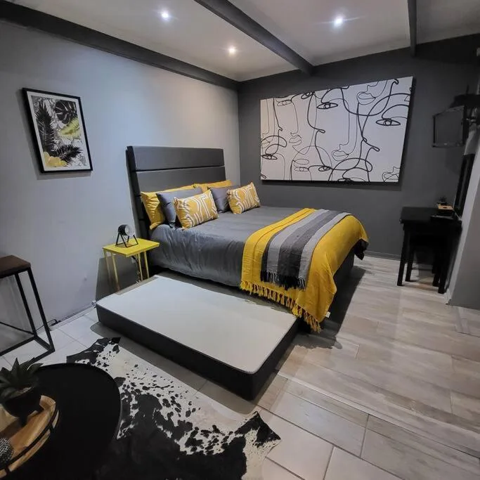 Modern bedroom with king bed, yellow accents, contemporary artwork, and ambient lighting