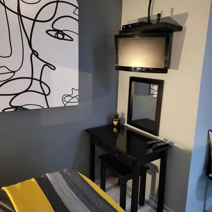 Modern bedroom corner with black desk, mounted TV, and abstract wall art