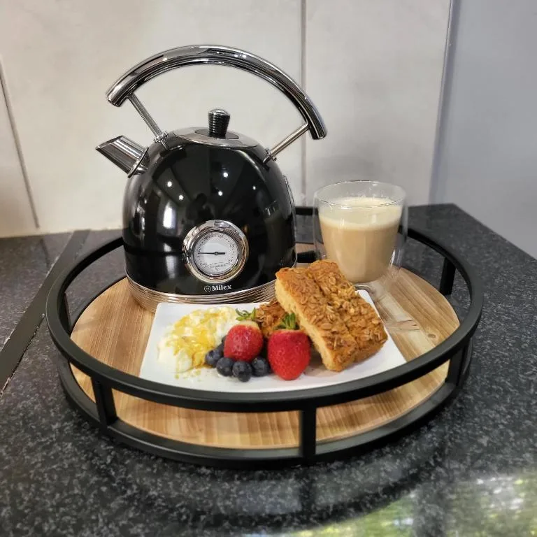In-room breakfast service with black kettle, fresh fruit, pastry and juice