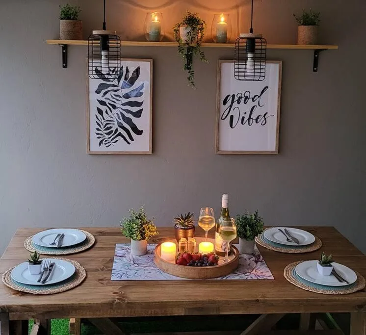 Elegantly styled dining table set for four with wine and decorative wall art