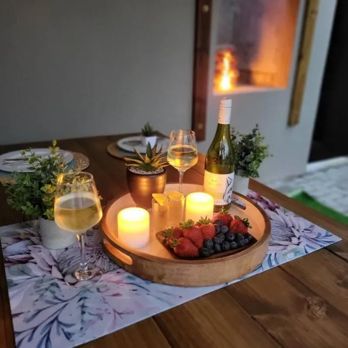 Elegantly set dining table with wine, candles, and fresh berries at dusk