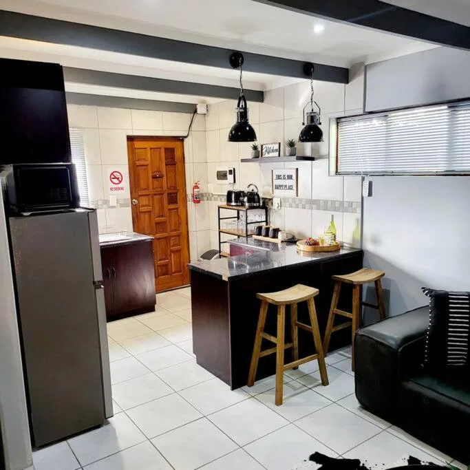Modern kitchen with black island, wooden stools, stainless steel appliances