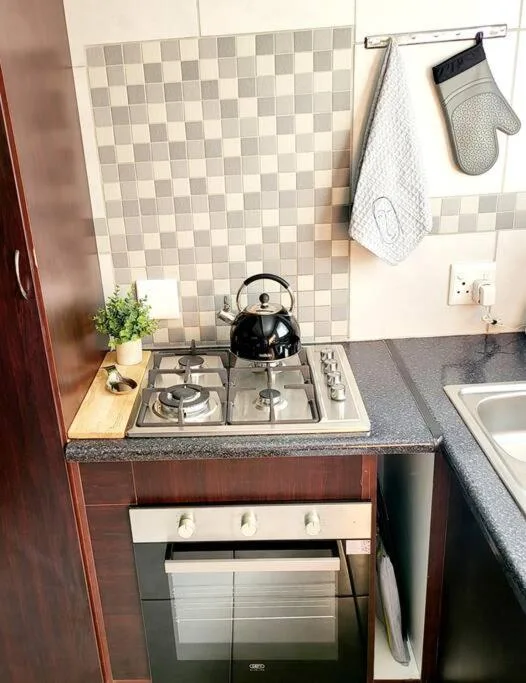 Compact kitchen with gas cooktop, oven, and checkerboard tile backsplash