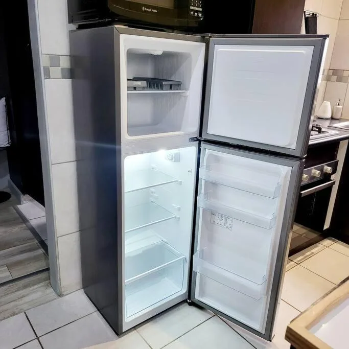 Open refrigerator with freezer compartment in bright kitchen space
