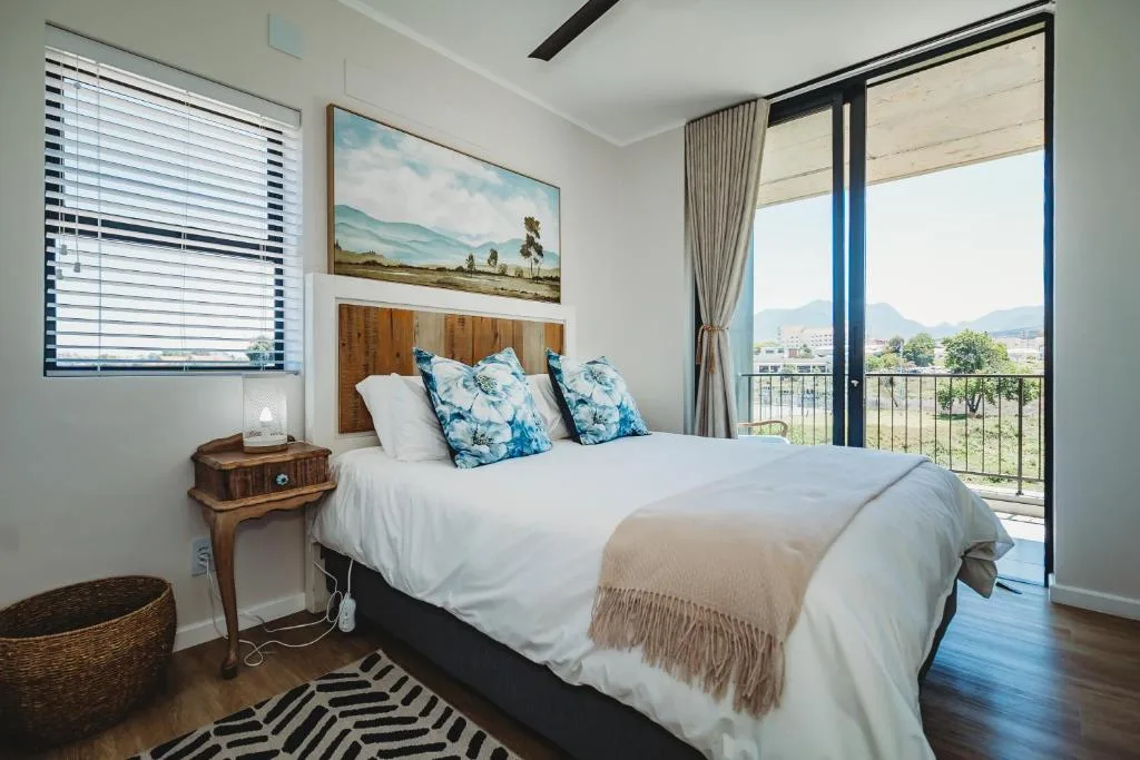 Bright bedroom with mountain views, white bedding, blue patterned pillows, wooden headboard