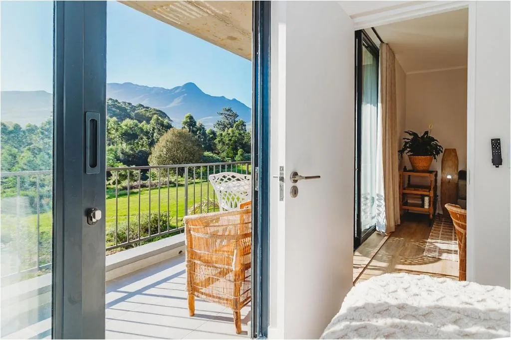 Bright bedroom with mountain view through open sliding glass doors to deck