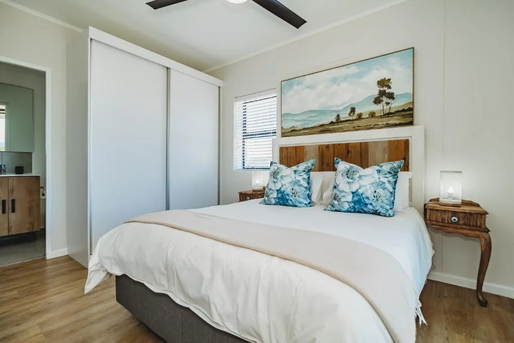 Spacious bedroom with queen bed, blue patterned pillows, wooden headboard, and ensuite access