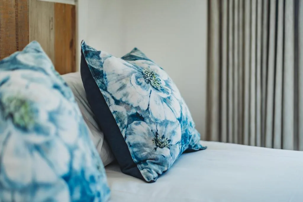 Bed with blue floral pillows and white linens in bright bedroom