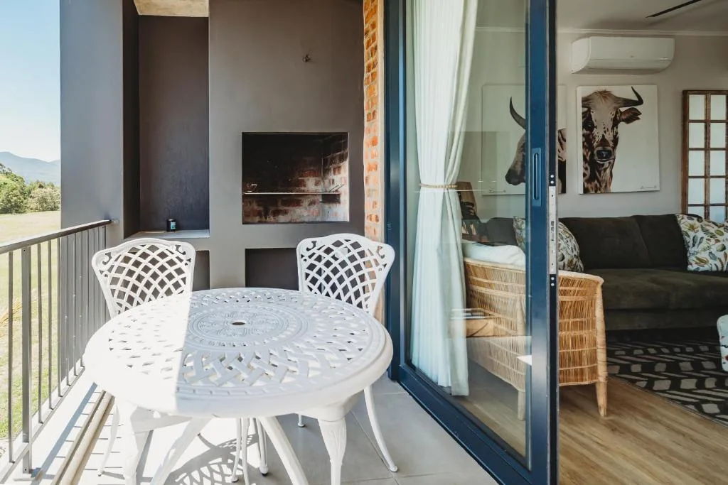 Outdoor patio with white metal table and chairs overlooking mountains