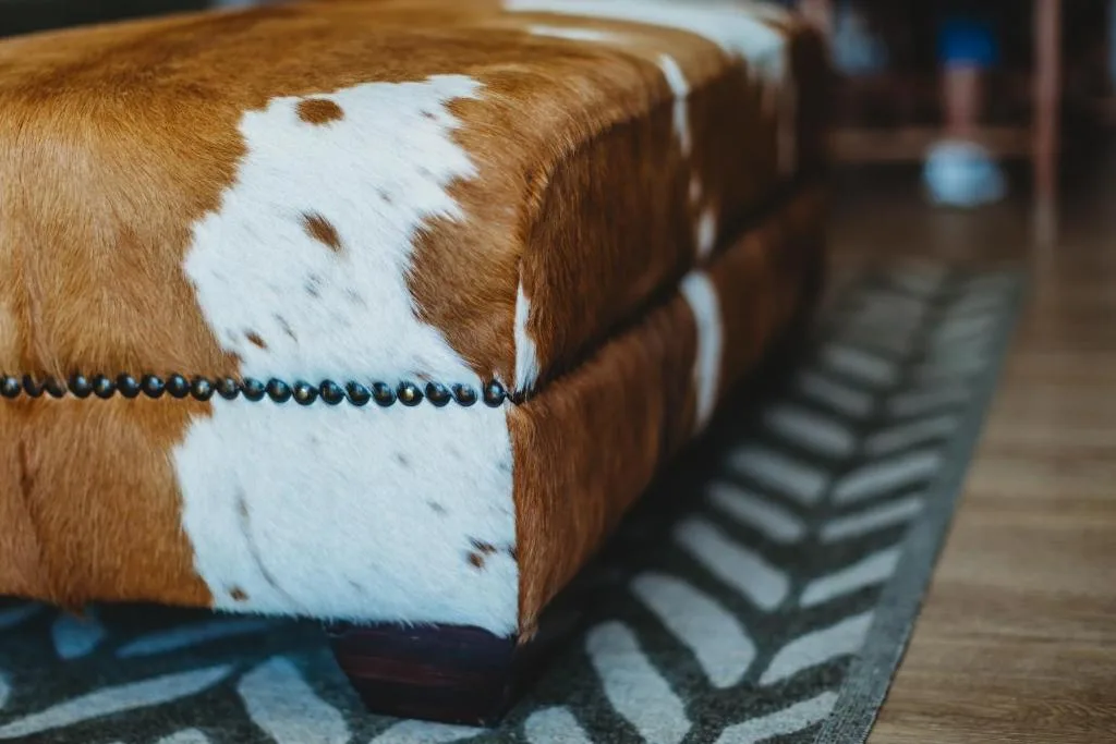 Close-up of cowhide ottoman with decorative beading trim detail