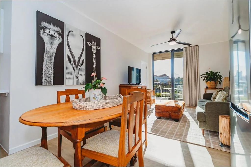 Wooden dining table with chairs, lounge area and mountain views beyond