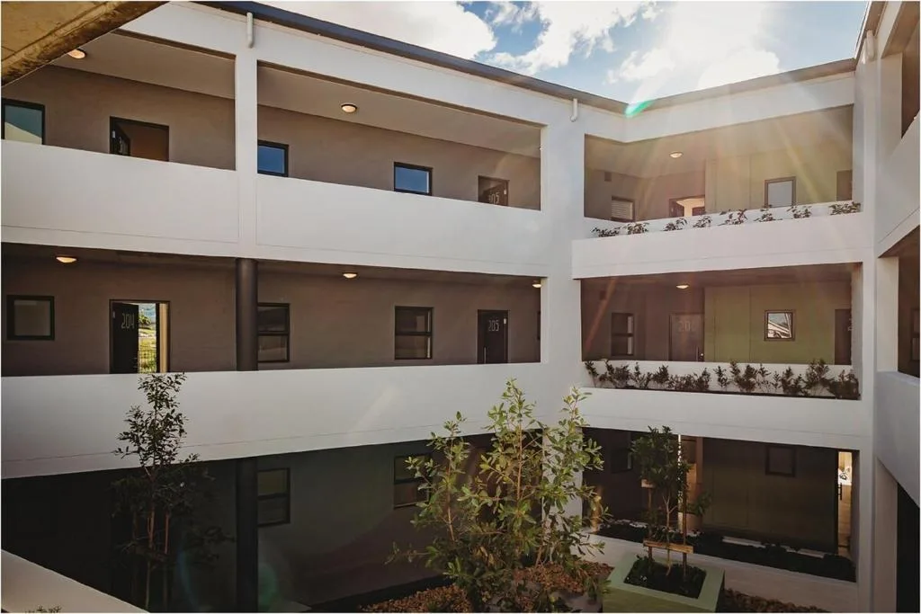 Modern multi-story residential building with white balconies and central courtyard garden