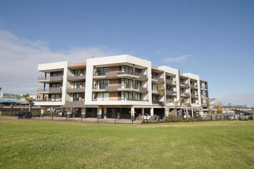 Modern white apartment building with balconies overlooking green lawn
