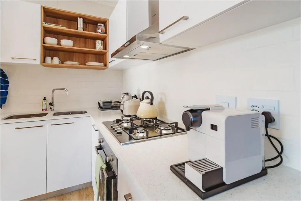 Modern kitchen with gas stove, white cabinetry, and wooden shelving