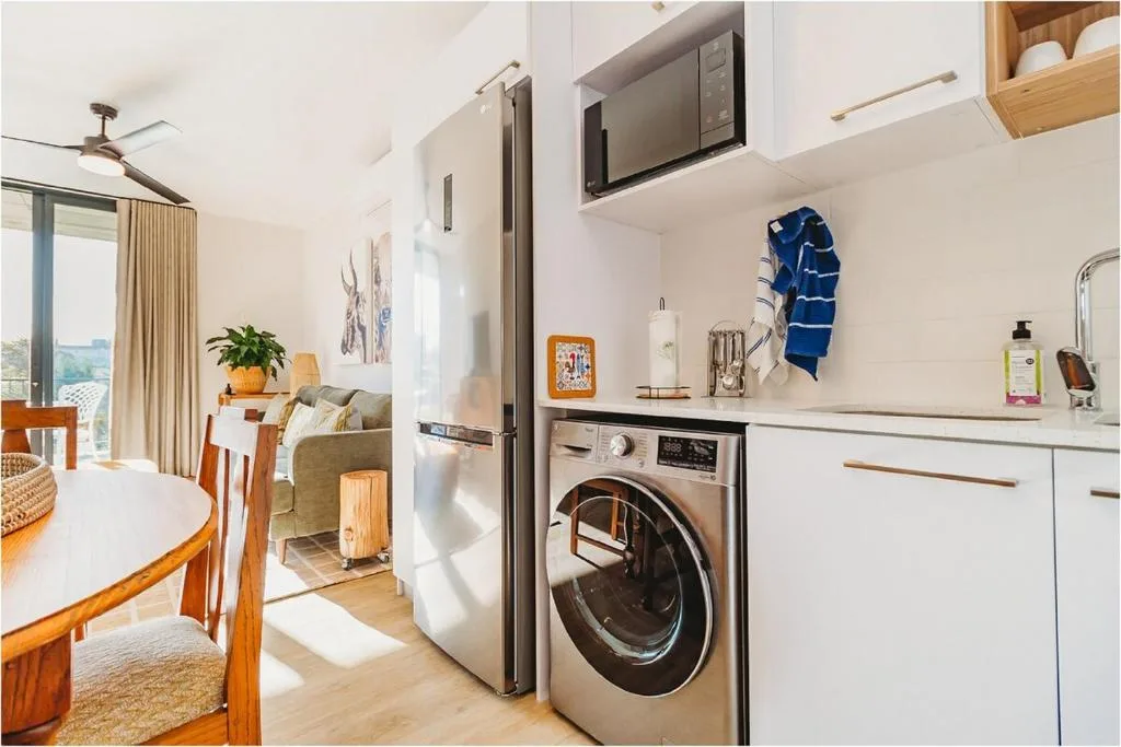 Modern kitchen with washing machine, microwave, and white cabinetry