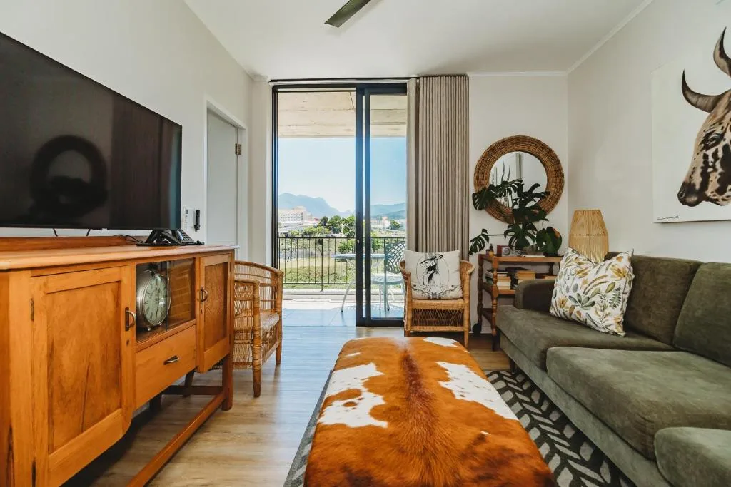 Spacious lounge with green sofa, wooden furniture, mountain views through glass doors