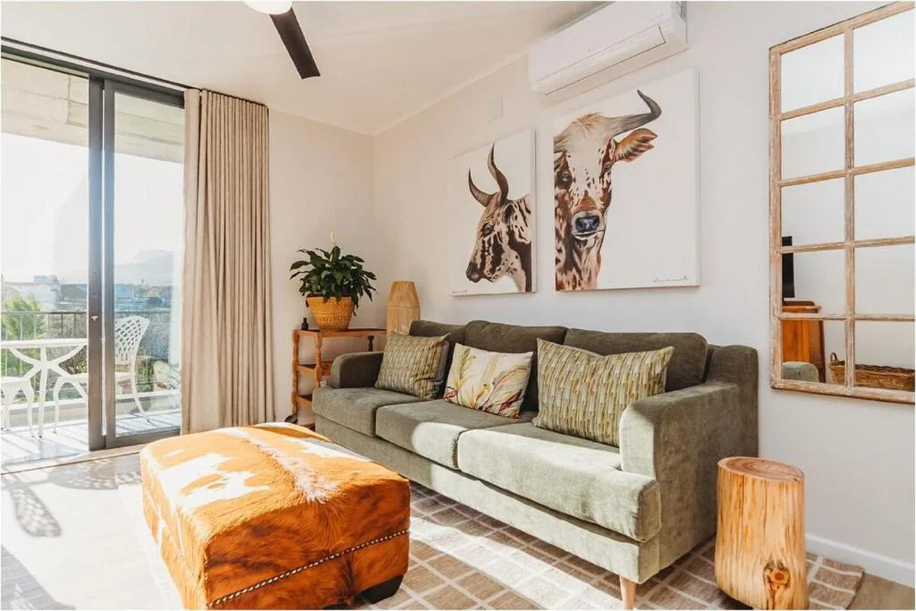 Modern lounge with gray sofa, wildlife artwork, and mountain views through glass doors