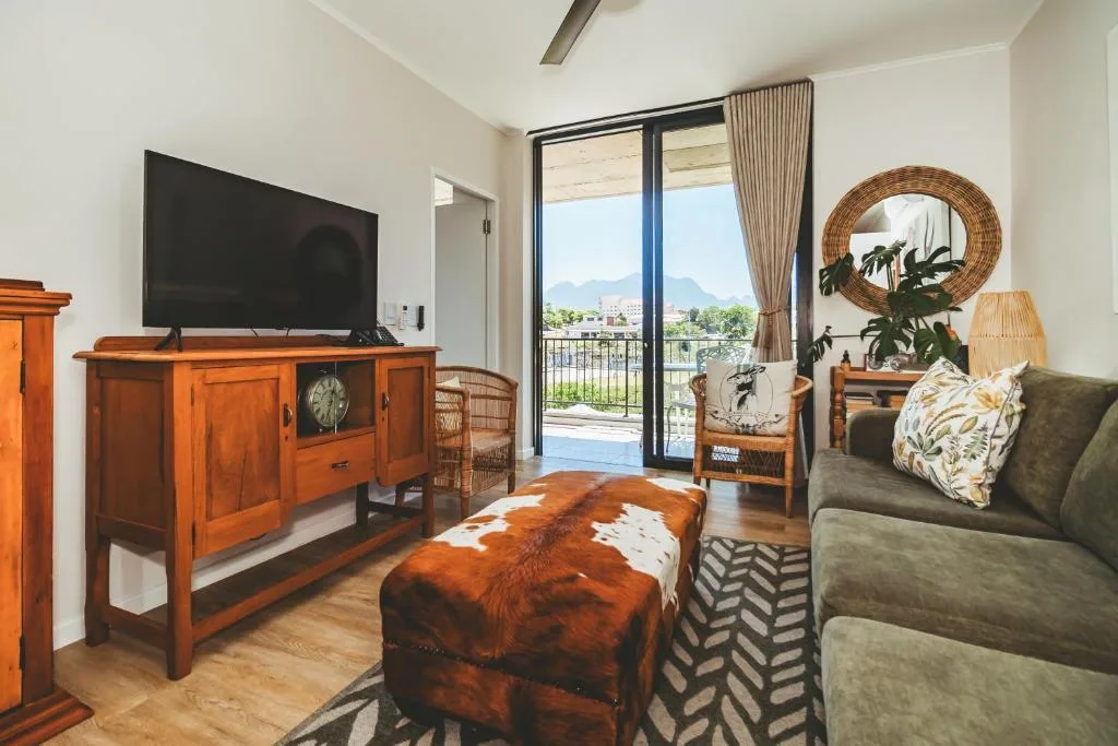 Modern lounge with flat-screen TV, wooden furniture, and mountain views through glass doors